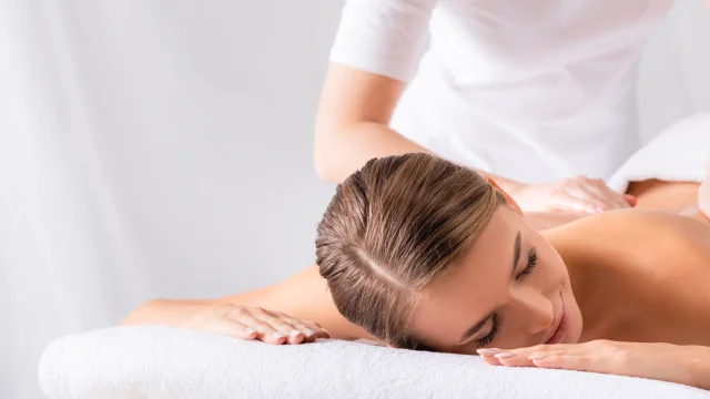 masseur masseert tevreden jonge vrouw op massagetafel in spa salon, banner