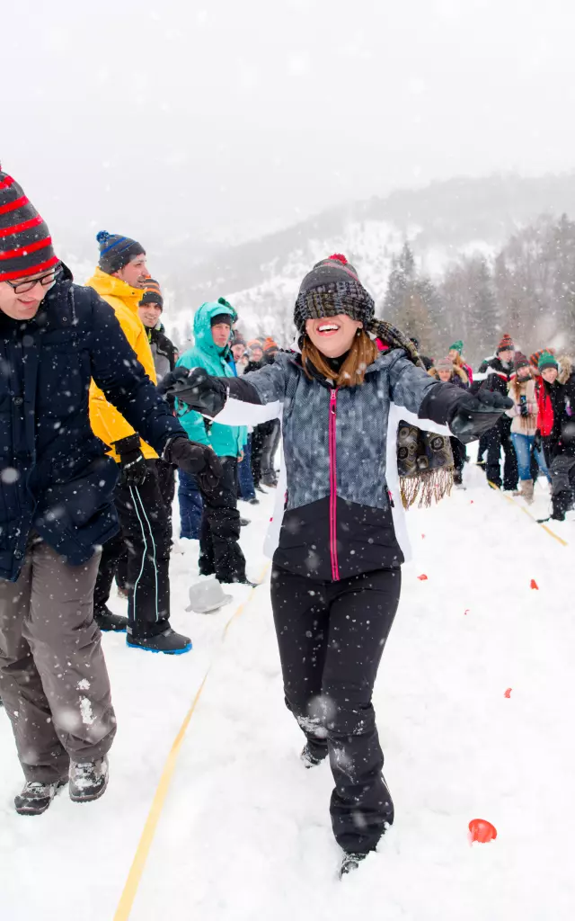 group of young happy business people having a Blindfolded games competition while enjoying snowy winter day with snowflakes around them during a team building in the mountain forest