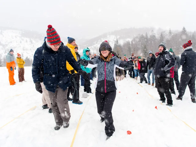group of young happy business people having a Blindfolded games competition while enjoying snowy winter day with snowflakes around them during a team building in the mountain forest