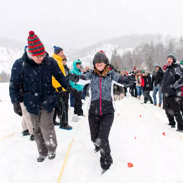 group of young happy business people having a Blindfolded games competition while enjoying snowy winter day with snowflakes around them during a team building in the mountain forest