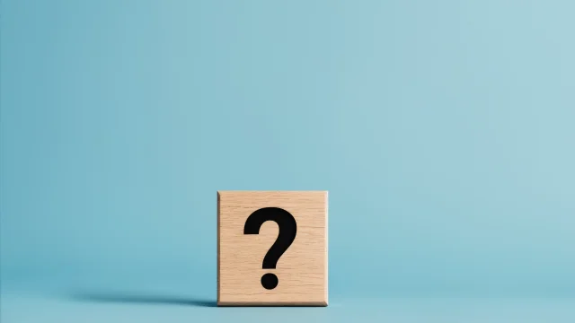 Punto interrogativo su blocco di legno su sfondo blu